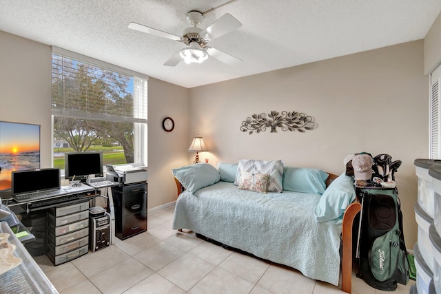 bedroom with ceiling fan, baseboards, a textured ceiling, and light tile patterned flooring