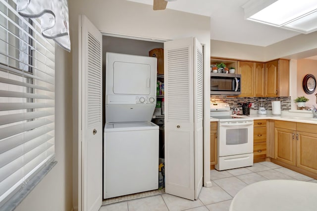 kitchen with light countertops, backsplash, white range with electric stovetop, stainless steel microwave, and stacked washer and clothes dryer