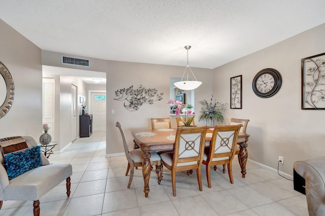 dining area featuring a textured ceiling, light tile patterned floors, visible vents, and baseboards