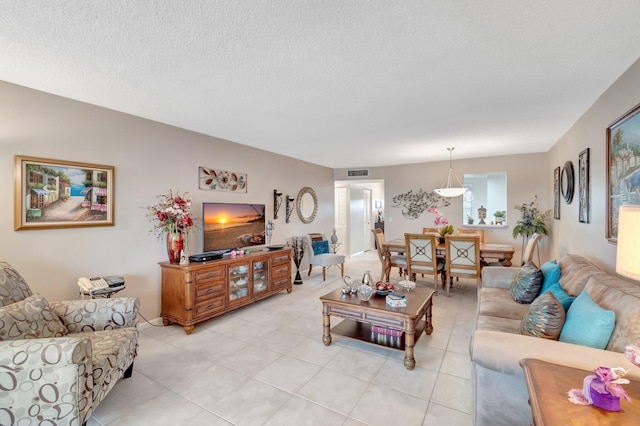 living area featuring a textured ceiling, light tile patterned floors, and visible vents