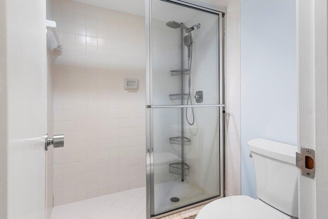 bathroom featuring a shower with door and toilet