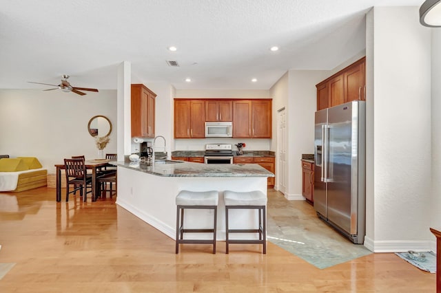 kitchen featuring appliances with stainless steel finishes, a breakfast bar, sink, dark stone countertops, and kitchen peninsula