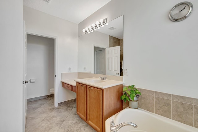bathroom with a bathing tub, vanity, tile patterned floors, and toilet