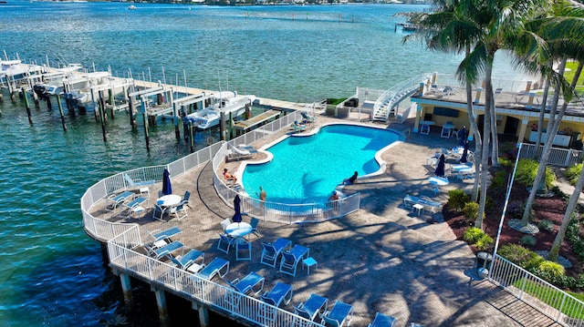view of swimming pool featuring a patio, a water view, and a dock