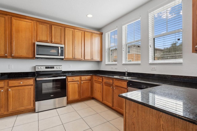 kitchen featuring light tile patterned floors, appliances with stainless steel finishes, sink, and dark stone countertops