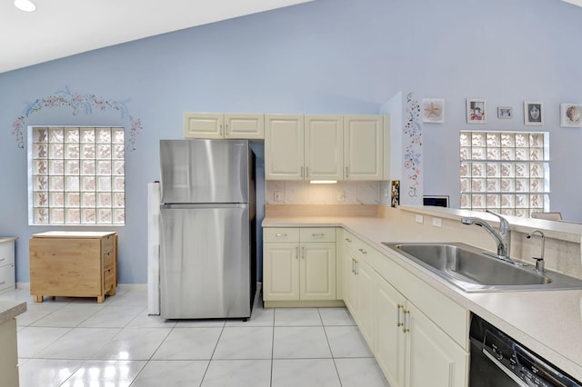 kitchen featuring cream cabinets, black dishwasher, stainless steel fridge, sink, and light tile patterned flooring