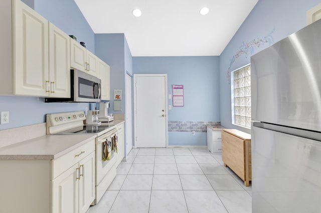 kitchen featuring appliances with stainless steel finishes, light tile patterned flooring, and white cabinets