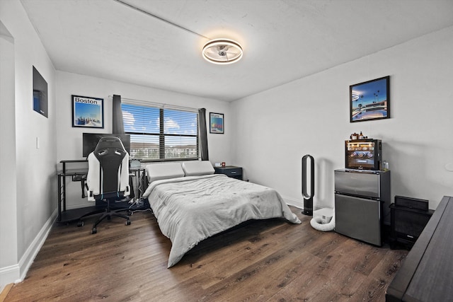 bedroom with stainless steel refrigerator and dark hardwood / wood-style flooring