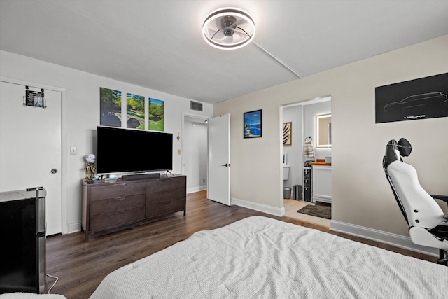 bedroom with ensuite bath and dark hardwood / wood-style floors