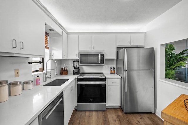 kitchen featuring sink, white cabinetry, stainless steel appliances, dark hardwood / wood-style floors, and a textured ceiling