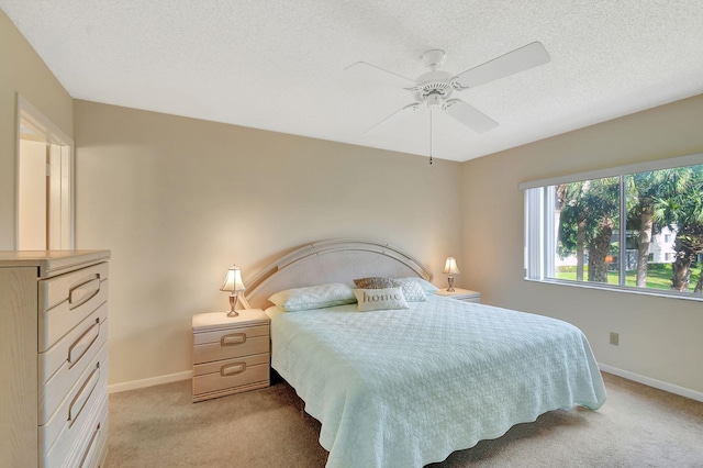 carpeted bedroom featuring ceiling fan and a textured ceiling