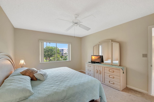 carpeted bedroom featuring ceiling fan and a textured ceiling