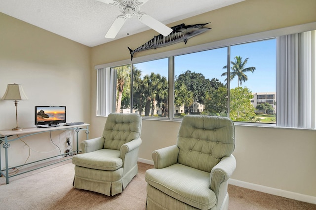 sitting room featuring ceiling fan, light colored carpet, and a textured ceiling