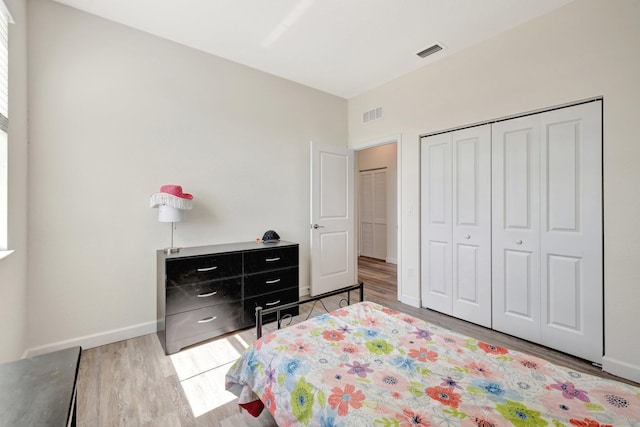 bedroom featuring a closet, visible vents, baseboards, and wood finished floors