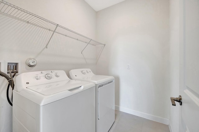 clothes washing area featuring laundry area, light tile patterned flooring, independent washer and dryer, and baseboards