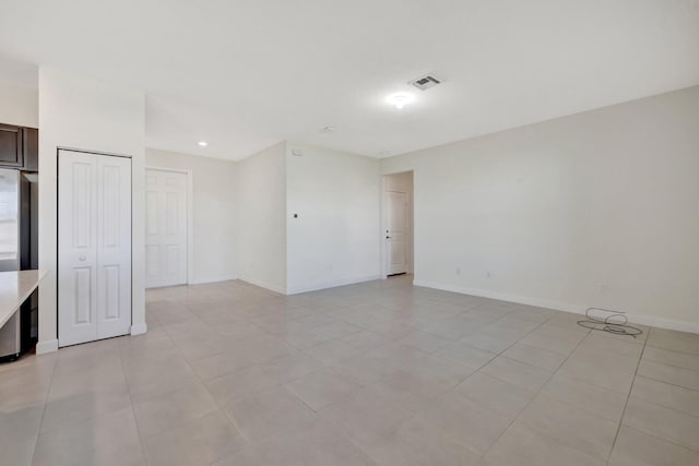 unfurnished room featuring baseboards, visible vents, and light tile patterned flooring