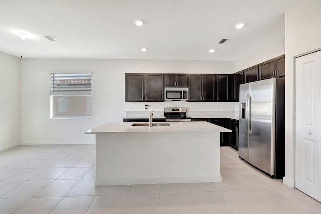 kitchen featuring a sink, visible vents, light countertops, appliances with stainless steel finishes, and an island with sink