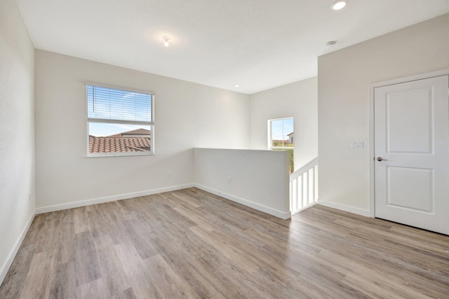 empty room featuring baseboards, recessed lighting, wood finished floors, and a healthy amount of sunlight