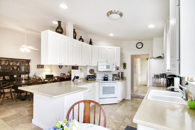 kitchen with a peninsula, white appliances, light countertops, and a sink