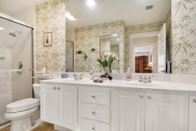 bathroom featuring double vanity, a sink, toilet, and wallpapered walls