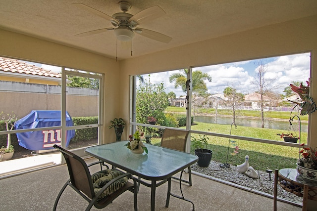 sunroom / solarium with a water view and a ceiling fan