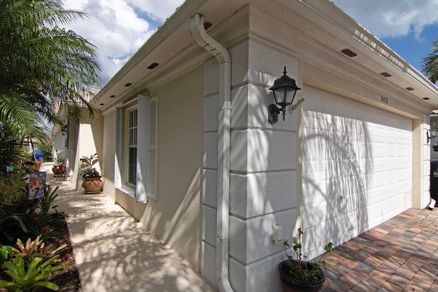 view of side of home featuring a garage, driveway, and stucco siding