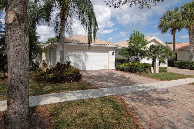 mediterranean / spanish-style home with a garage, a tiled roof, decorative driveway, and stucco siding