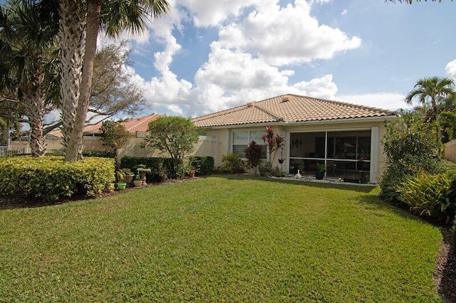 view of front facade featuring a tiled roof, a front yard, a sunroom, and stucco siding