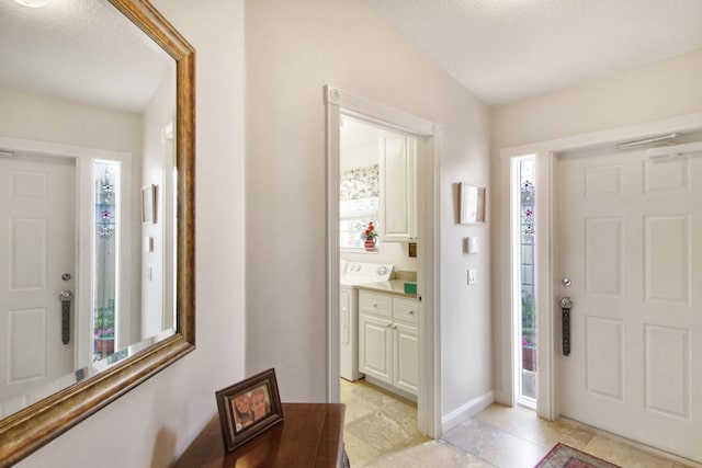 foyer entrance with washer / dryer and baseboards