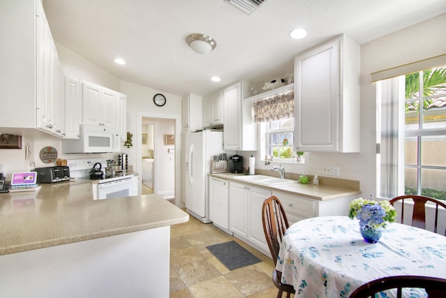 kitchen with white appliances, a sink, and white cabinets