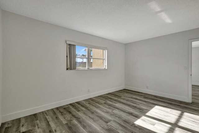 unfurnished room with hardwood / wood-style flooring and a textured ceiling