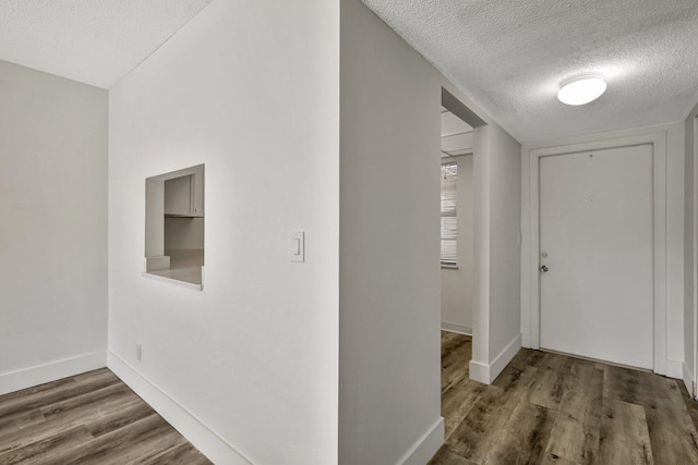 hall with dark wood-type flooring and a textured ceiling