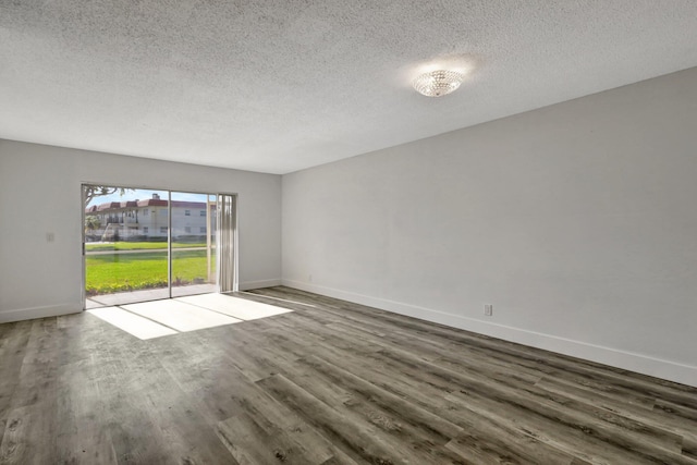 spare room featuring dark hardwood / wood-style floors and a textured ceiling