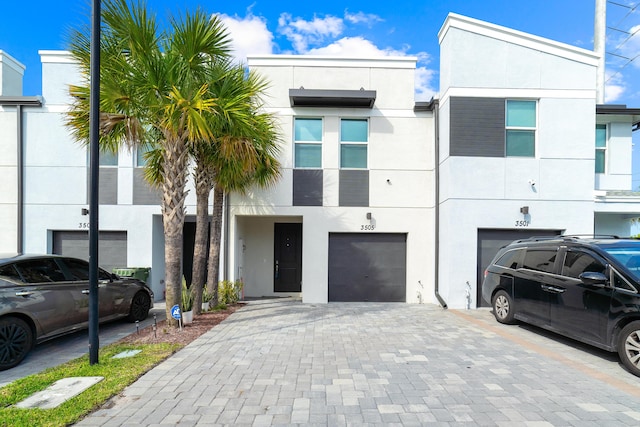 view of property with a garage, driveway, and stucco siding