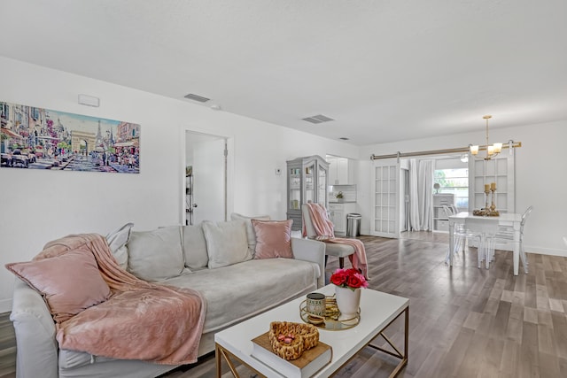 living room featuring wood-type flooring, a barn door, and a notable chandelier