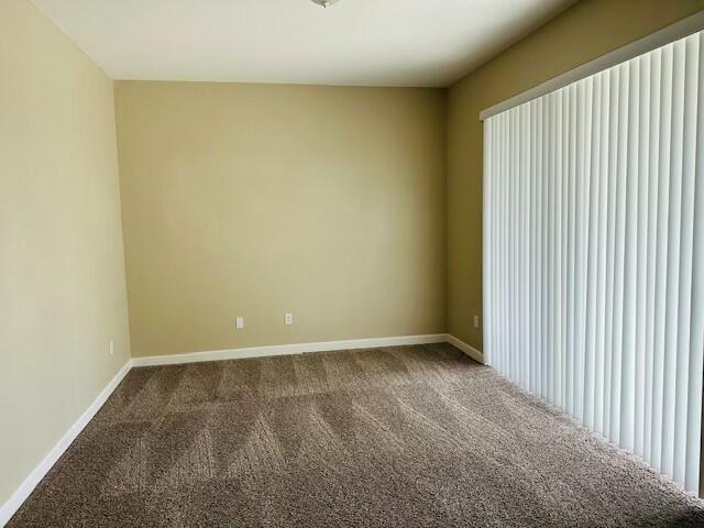 carpeted spare room featuring baseboards