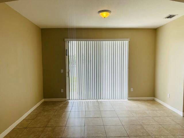 spare room featuring light tile patterned floors, visible vents, and baseboards