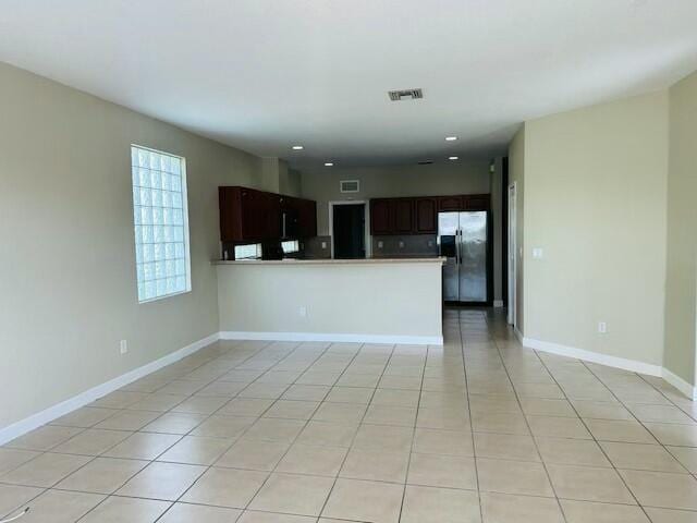 kitchen with light tile patterned floors, visible vents, baseboards, open floor plan, and stainless steel refrigerator with ice dispenser