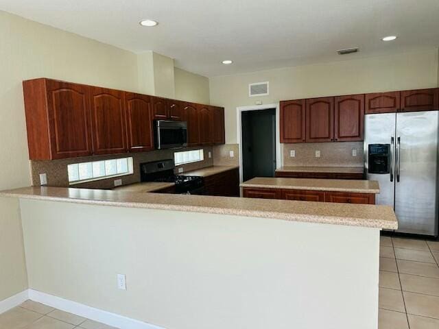 kitchen with a peninsula, light tile patterned floors, visible vents, and stainless steel appliances