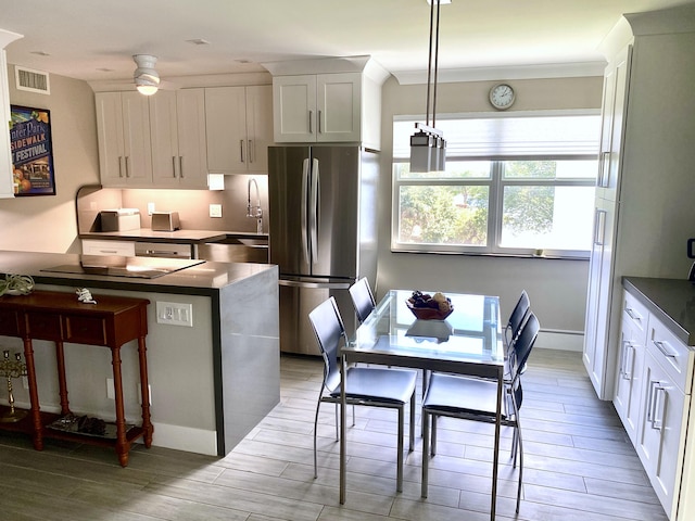 kitchen featuring pendant lighting, white cabinetry, stainless steel fridge, and sink