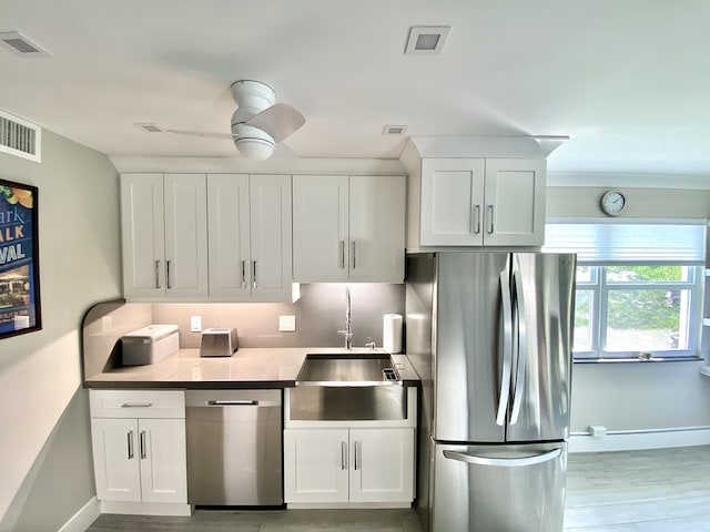 kitchen with white cabinetry, sink, stainless steel appliances, and ceiling fan