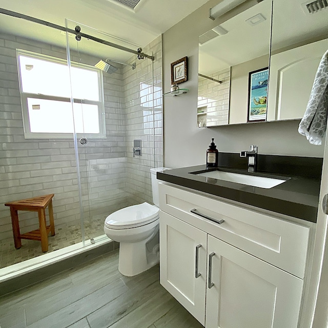 bathroom with vanity, wood-type flooring, a shower with shower door, and toilet