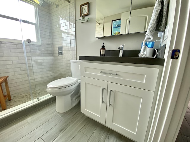 bathroom featuring hardwood / wood-style flooring, vanity, toilet, and walk in shower