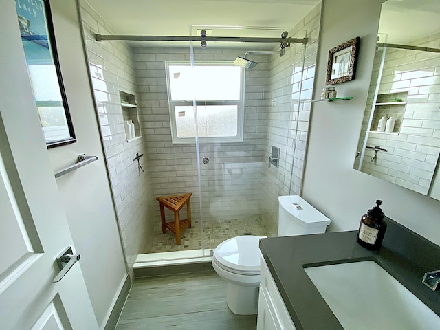 bathroom featuring vanity, hardwood / wood-style floors, a shower with door, and toilet