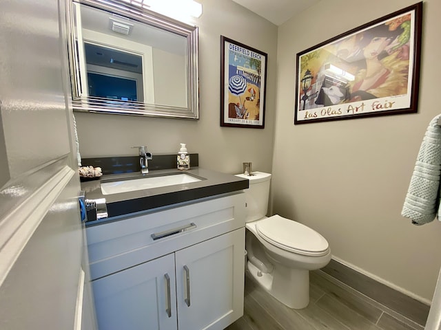 bathroom featuring vanity, hardwood / wood-style flooring, and toilet