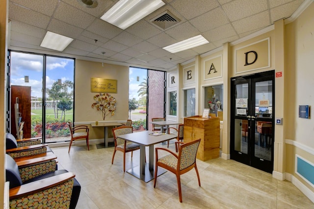 interior space with french doors, a wall of windows, elevator, and a drop ceiling