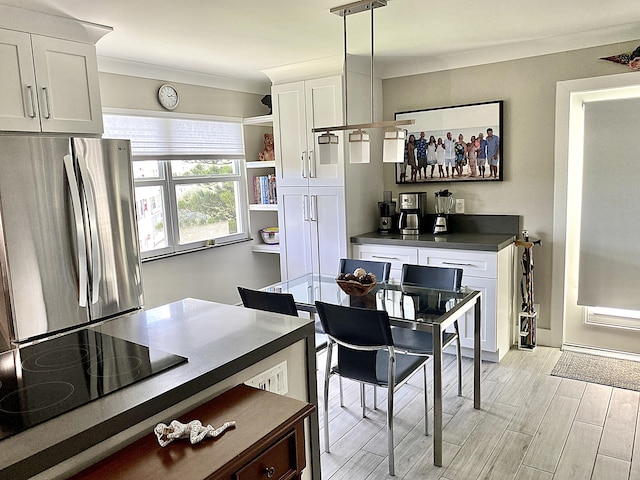 kitchen with hanging light fixtures, white cabinetry, black electric cooktop, and stainless steel refrigerator