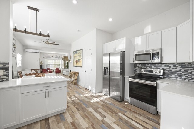 331 NW 1st Ave, Boynton Beach, FL 33435 - kitchen featuring appliances with stainless steel finishes, an AC wall unit, tasteful backsplash, white cabinetry, and hanging light fixtures