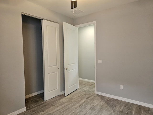 unfurnished bedroom with wood-type flooring, ceiling fan, and a closet