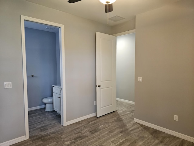 unfurnished bedroom featuring ceiling fan, dark wood-type flooring, and ensuite bath